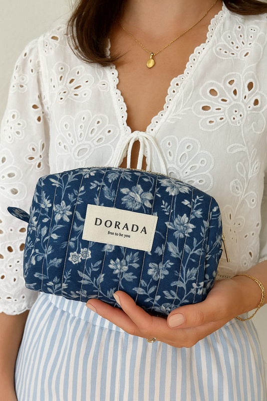 Person holding a blue floral-patterned pouch with 'DORADA' branding.